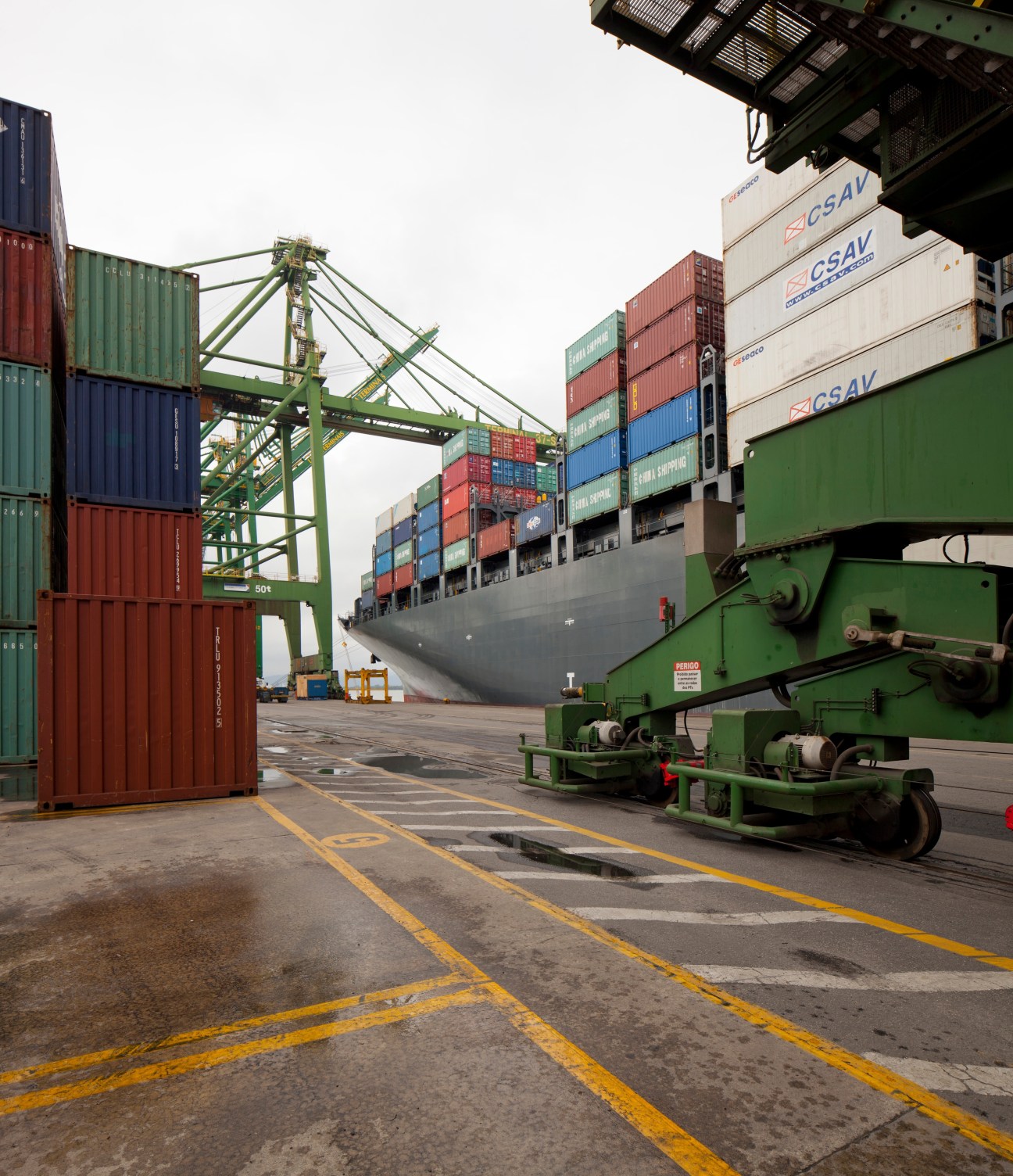 Cargo ship and containers at Santos port with green loading crane and stacked shipping containers.