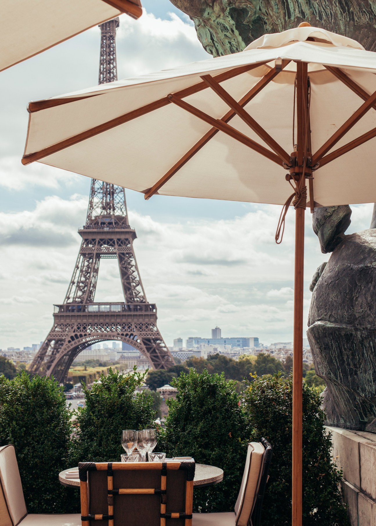 Café de l'Homme terrace with cream umbrellas overlooking the Eiffel Tower in Paris.