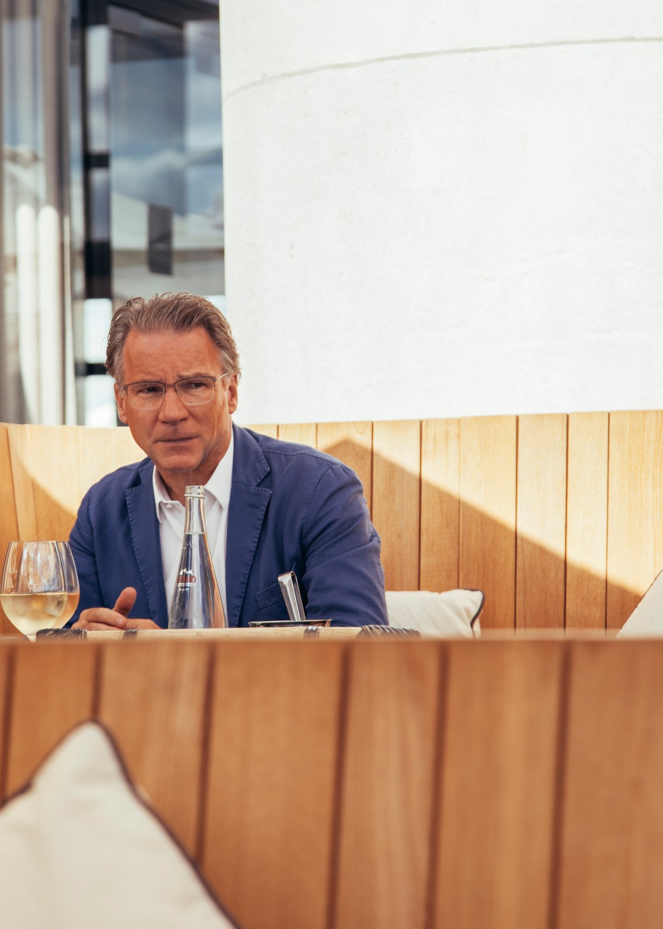 Olivier Royant, editor in chief of Paris Match, seated at a wooden booth in a restaurant.