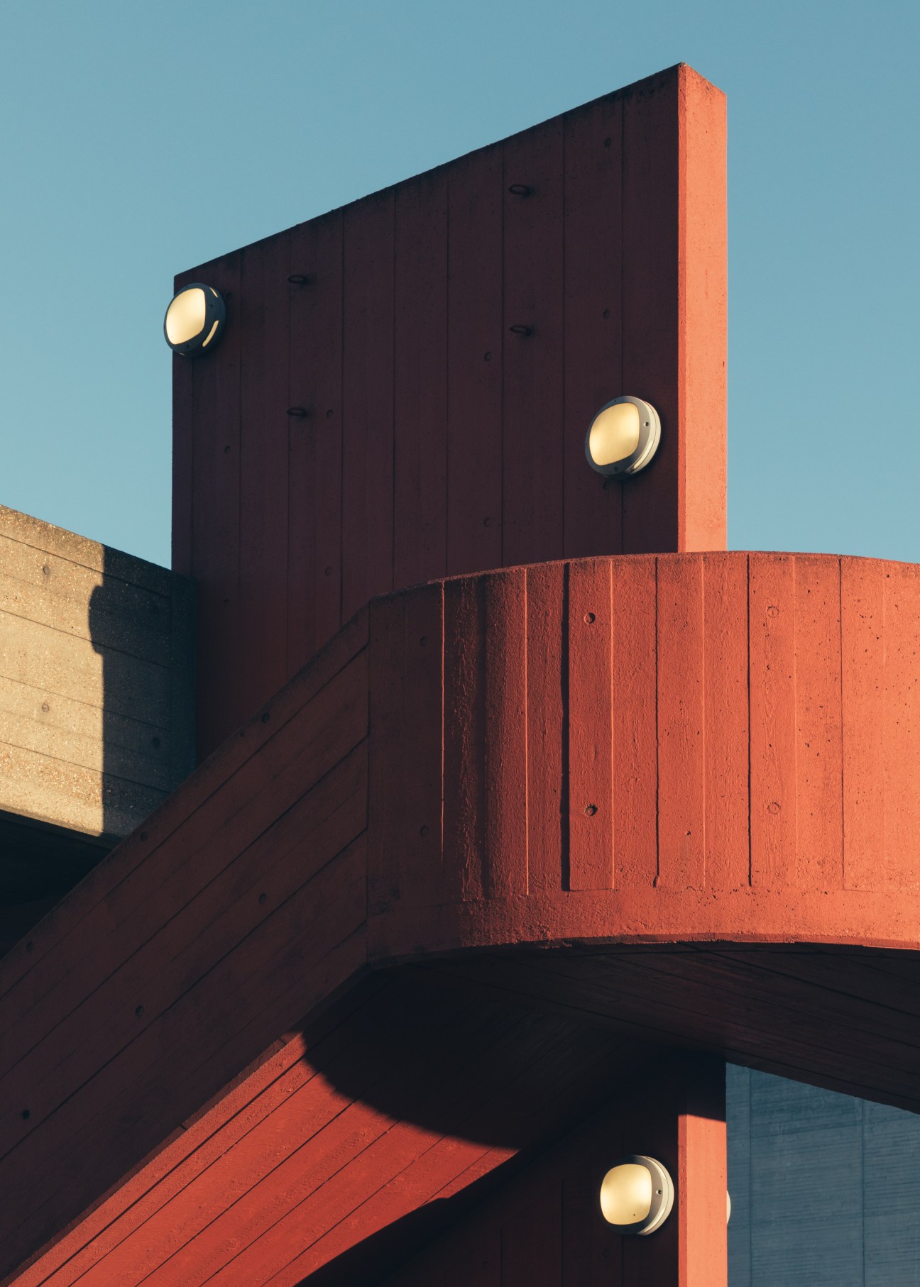 Brutalist concrete exterior staircase of the Hayward Gallery with round lights against a blue sky.
