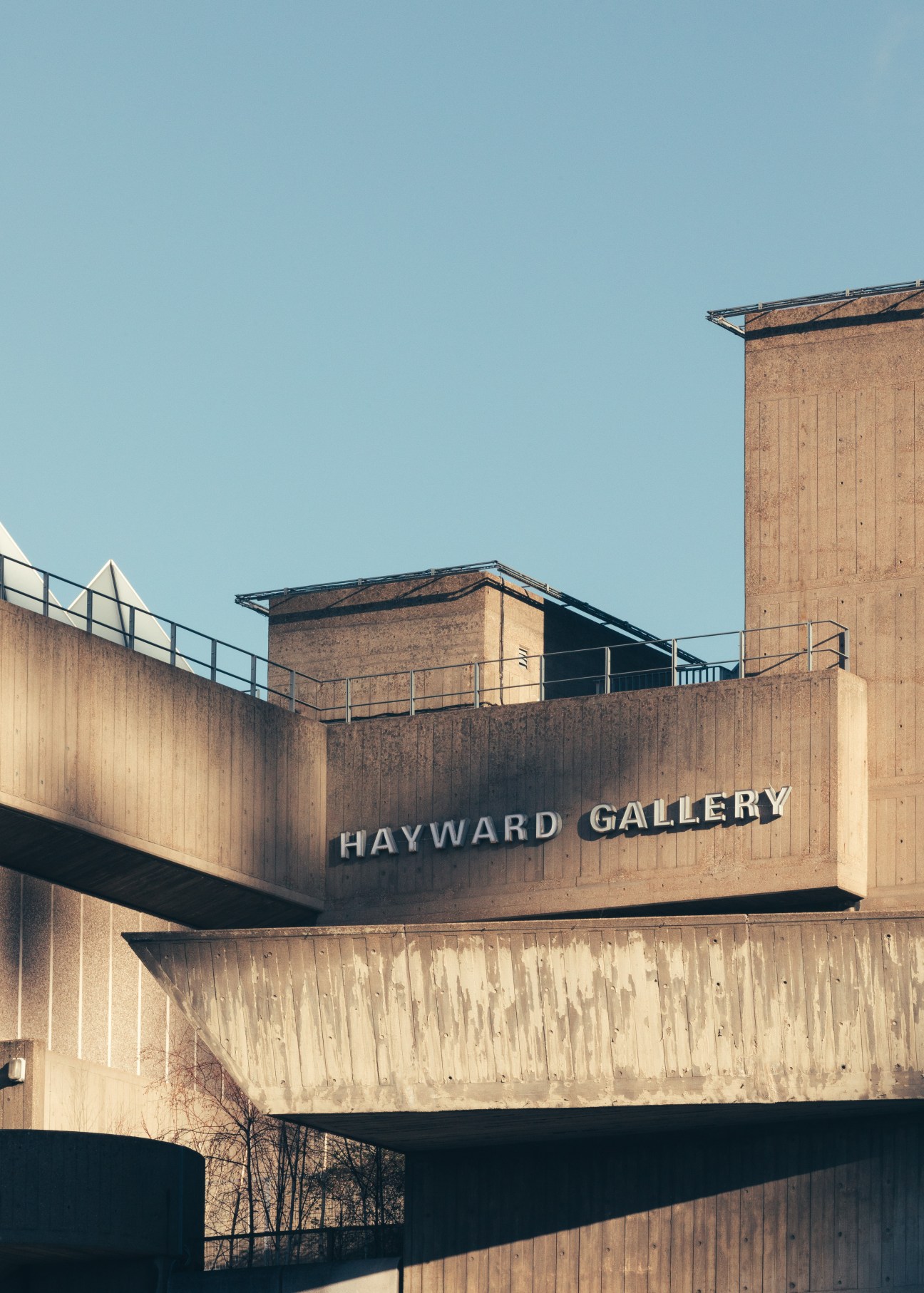 Exterior view of the Hayward Gallery's brutalist concrete facade with pyramid rooflights against a clear blue sky.
