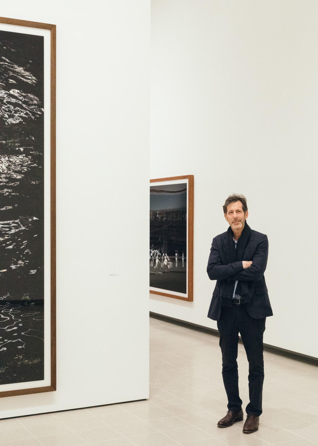 Ralph Rugoff, Hayward Gallery director, stands in the gallery with framed photographs on white walls.