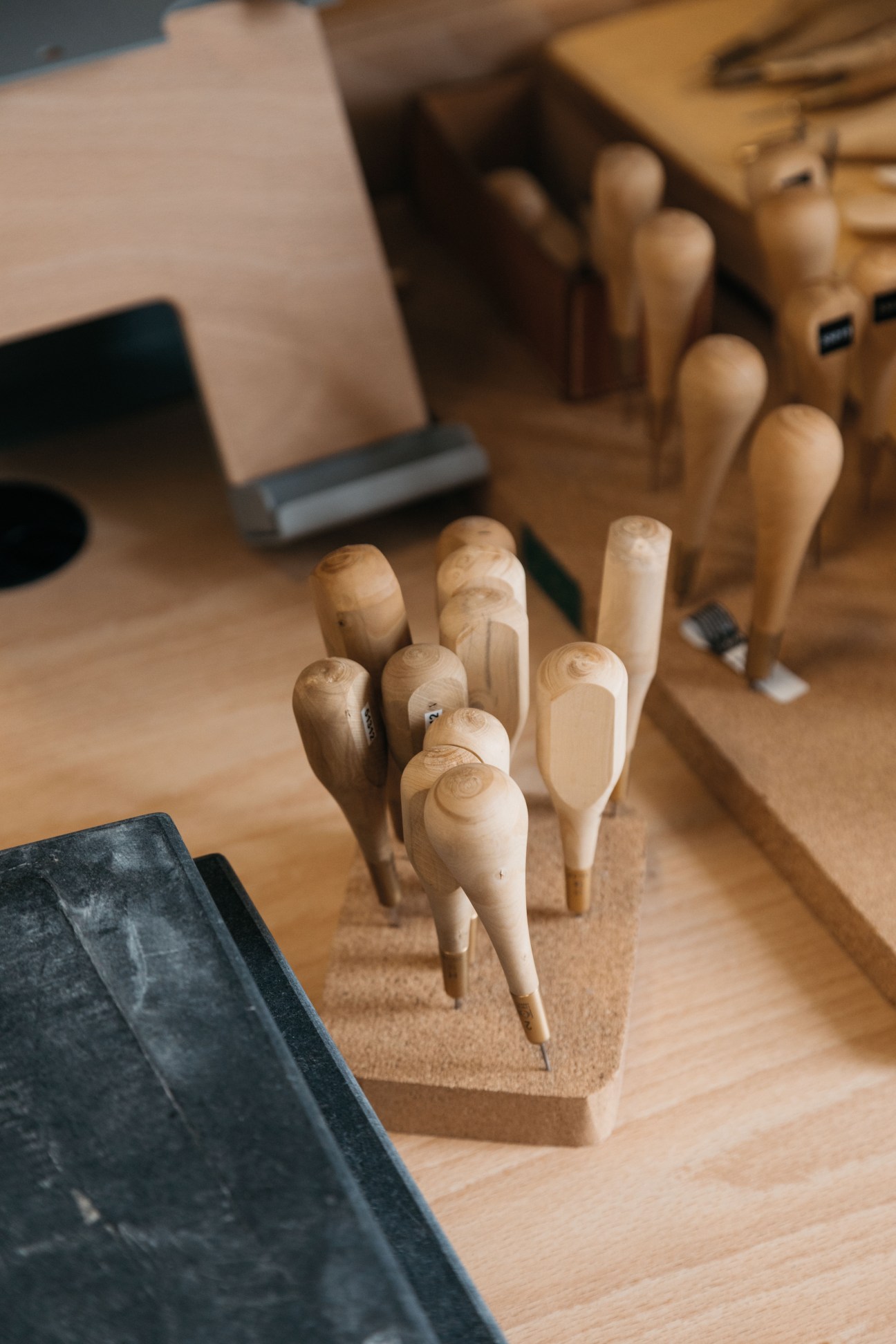 Wooden awls and leather-working tools arranged on a workbench at Hermès factory.