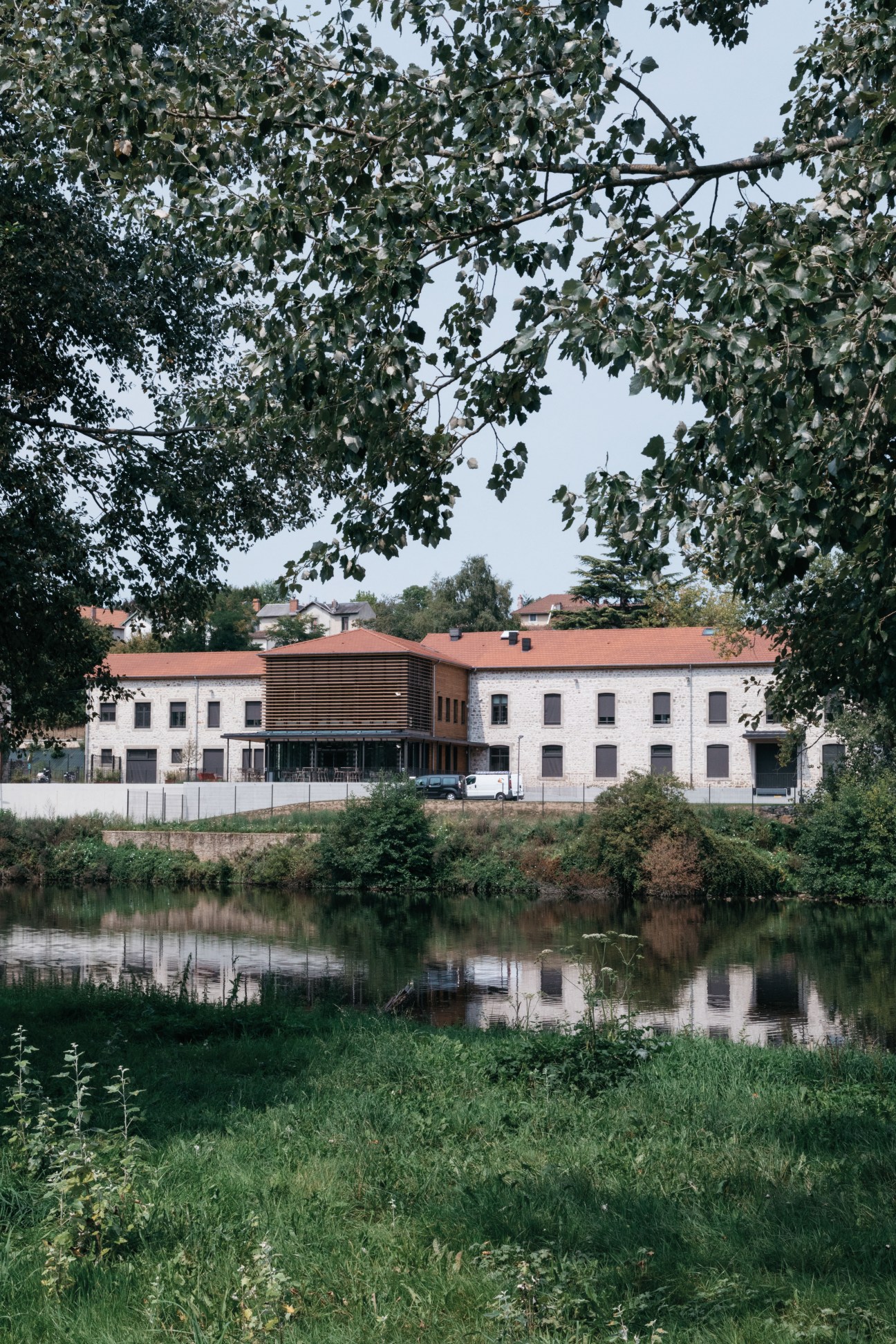 Hermès glove factory in Saint-Junien on the banks of the Vienne River with white stone buildings and terracotta roof.