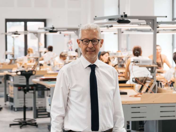 Thierry Thomé, director of the ganterie, stands in the Hermès leather goods workshop in Saint-Junien with artisans working at tables in the background.