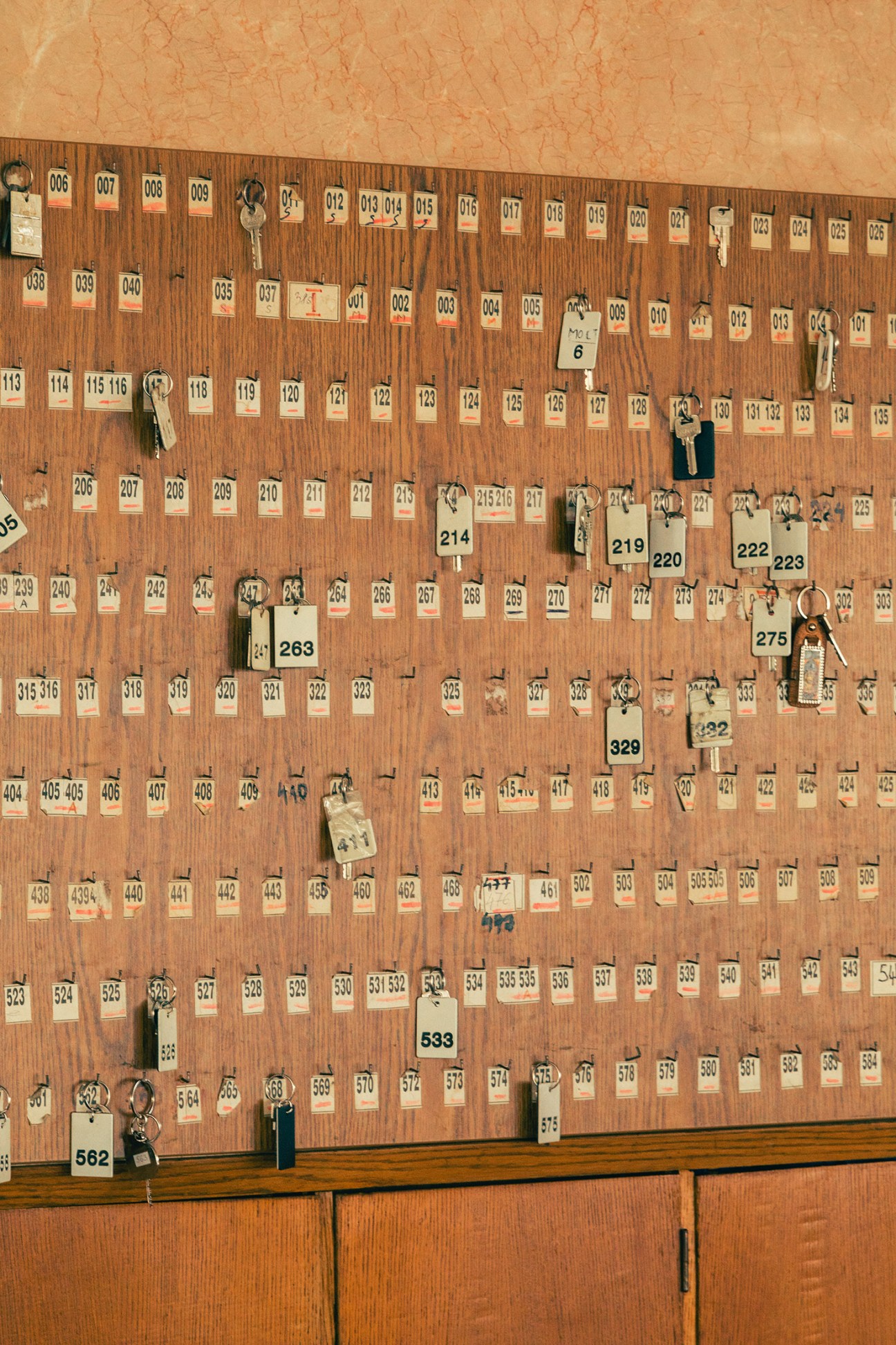 Wooden wall panel displaying hundreds of numbered office keys hanging from hooks at the Palace of Serbia.