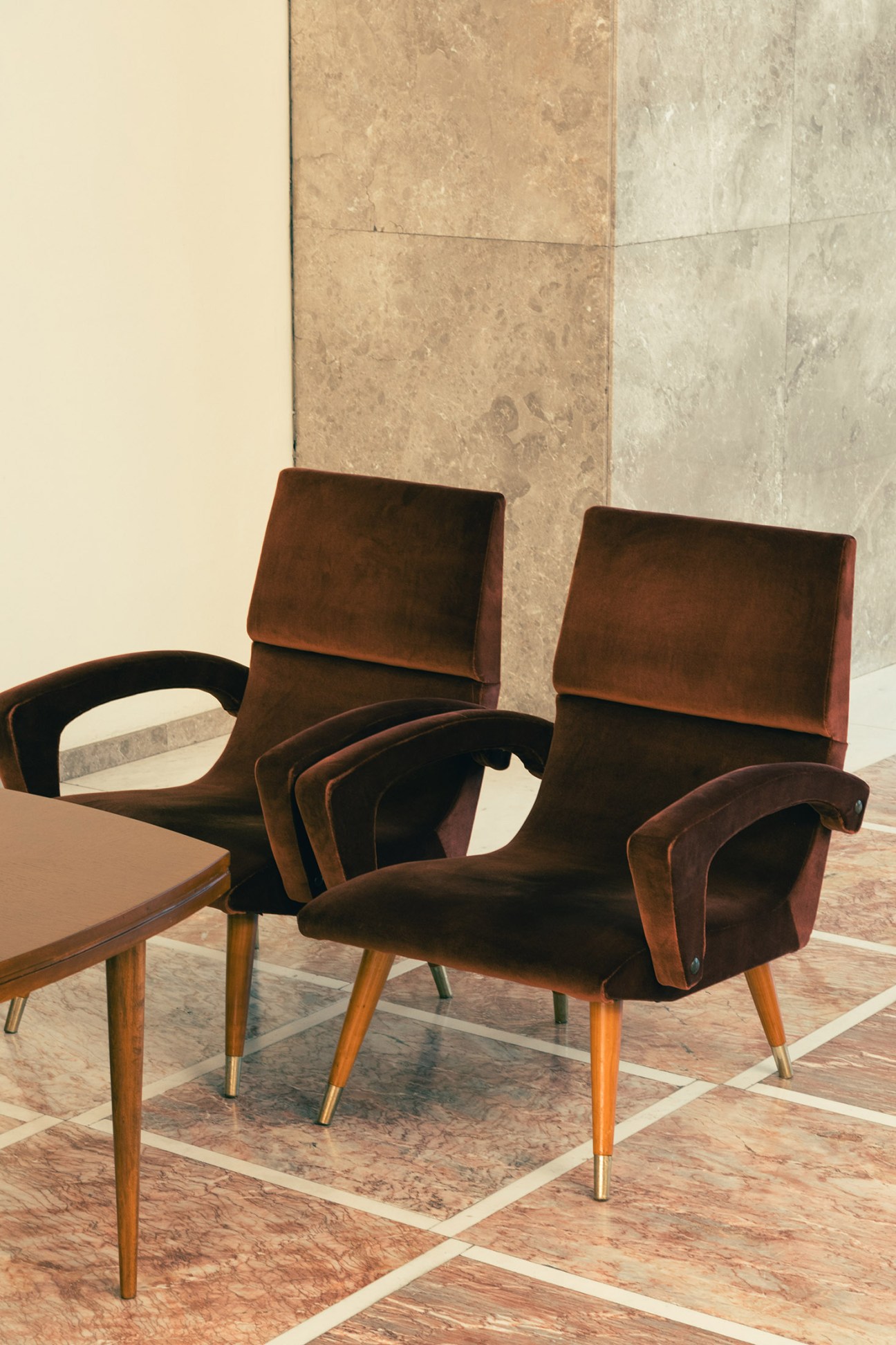 Mid-century modern chairs with brown upholstery and wooden legs in the Palace of Serbia's interior.