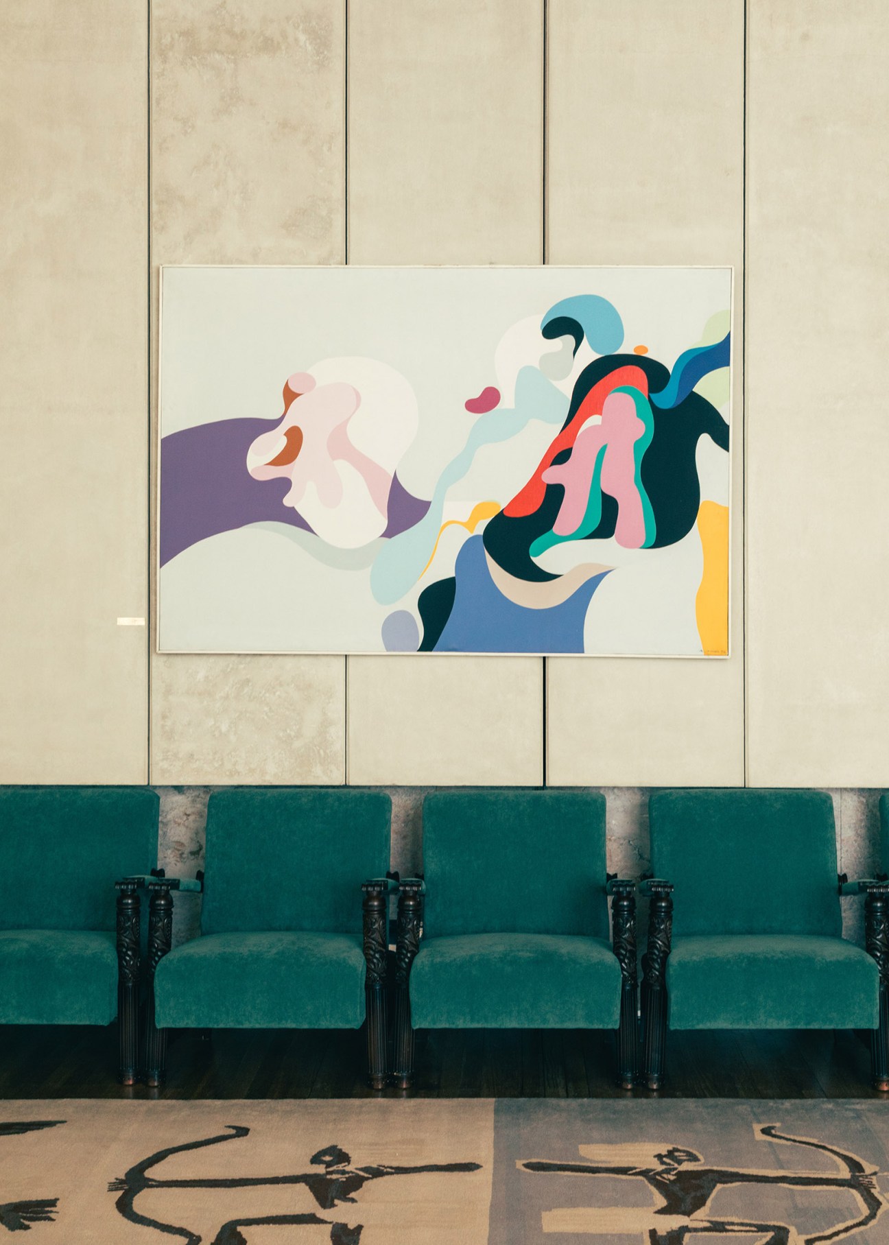 Colorful abstract expressionist artwork displayed on a beige wall above green velvet seating in the Slovenian chamber.
