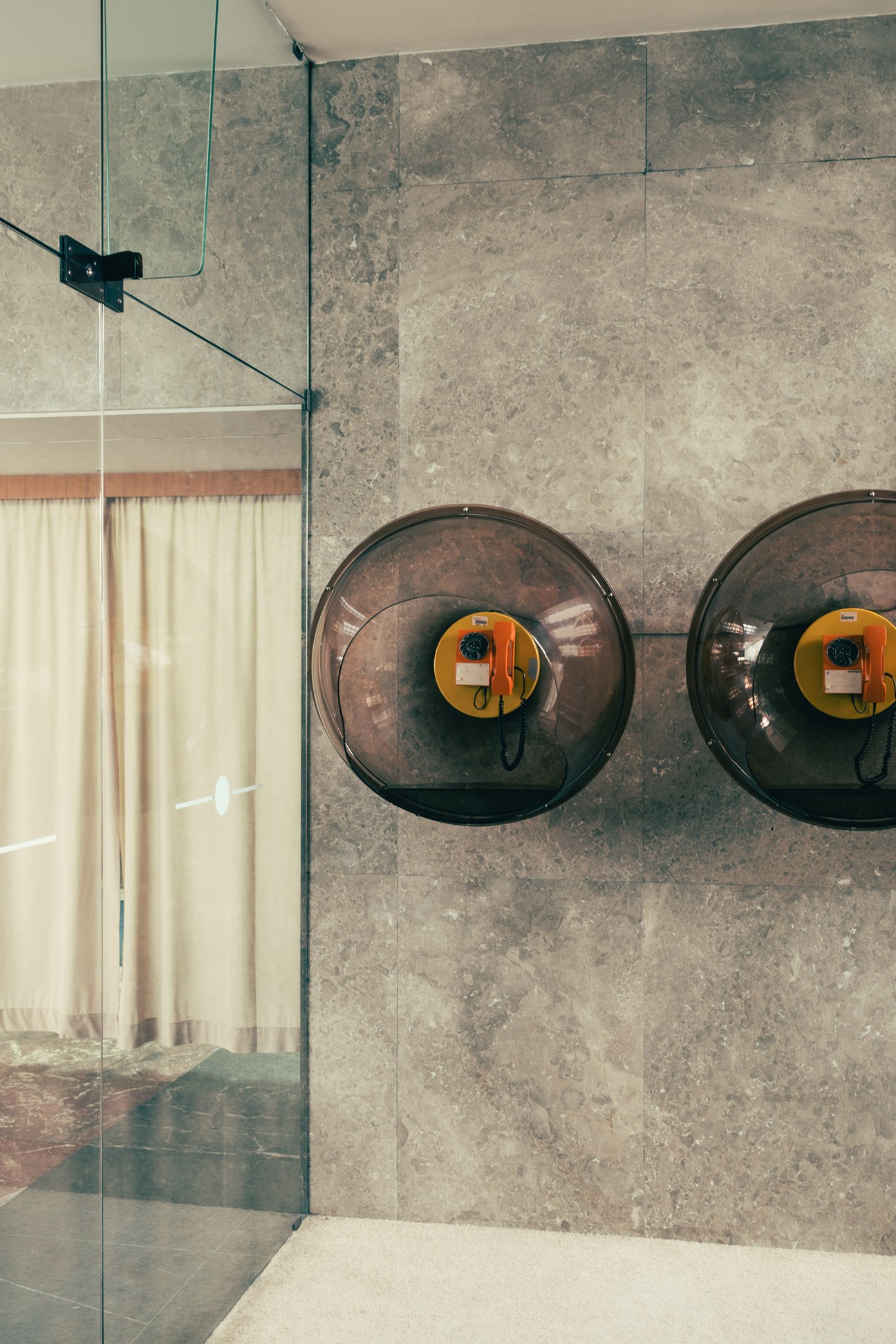 Two vintage rotary phone booths with orange and yellow centers mounted on a stone wall.