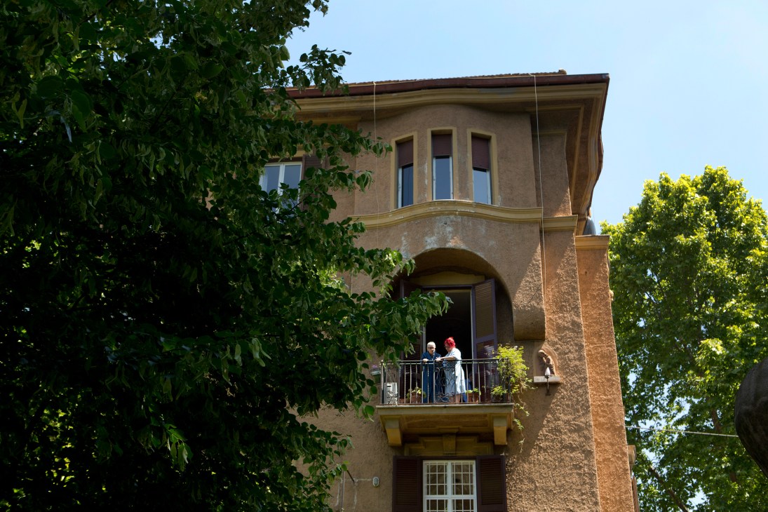 Ivy-covered terracotta building with two people on a balcony overlooking Villa Paganini in Rome's Trieste neighbourhood.