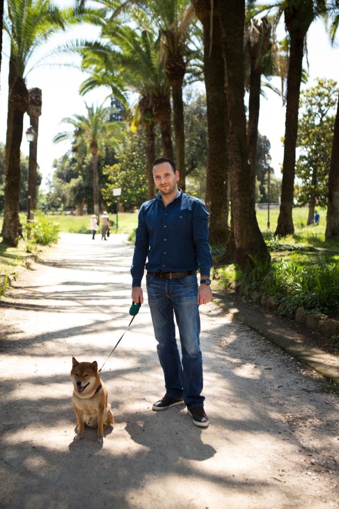 Man walking his dog on a tree-lined path in Villa Torlonia park, Rome.