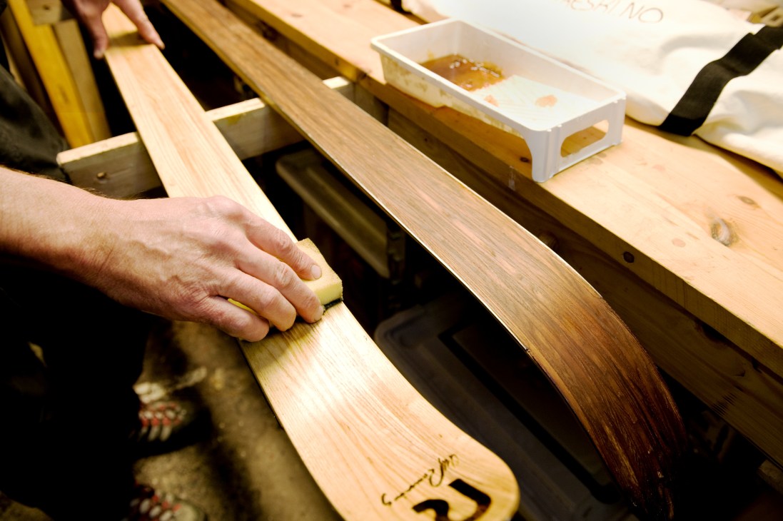A hand applying tree oil to wooden skis in the Rønning Ski factory workshop.