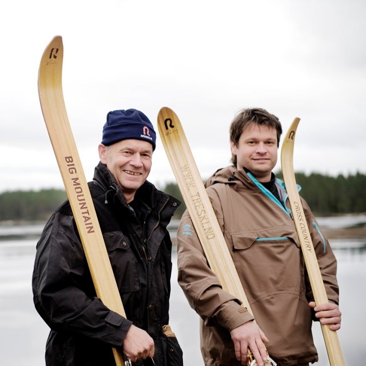 Ulf and Jonas Rønning hold wooden skis by a snowy lake in Norway.