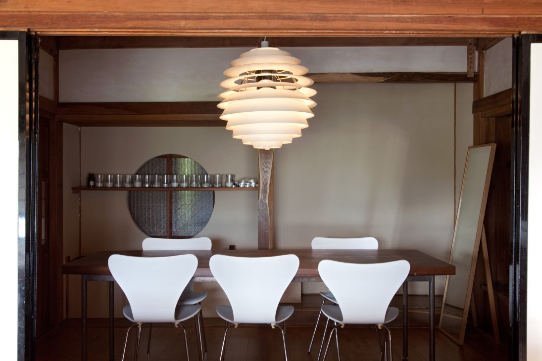Modern dining room with wooden table, white chairs, and a tiered pendant lamp above.