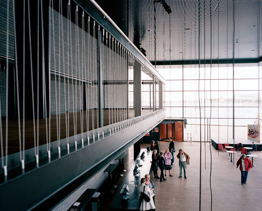 Interior balcony view of the Royal Playhouse with large windows and visitors below.