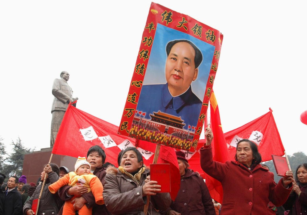 People holding red flags and a large portrait of Chairman Mao during a public celebration in China.