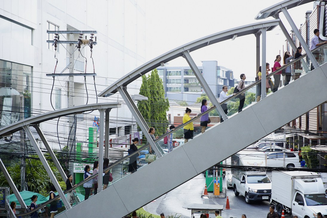 Commuters climbing metal stairs to Bangkok's Skytrain platform in Ari neighborhood.