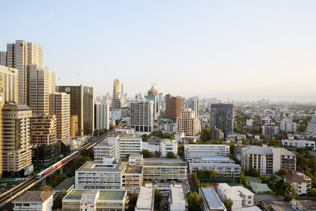 Aerial view of Bangkok's Ari neighborhood showing mid-rise buildings, green spaces, and elevated Skytrain infrastructure.