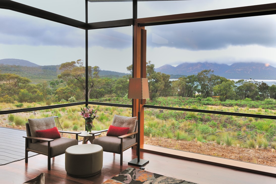 Interior lounge area at Saffire Hotel with floor-to-ceiling windows overlooking Tasmanian bay and mountains.