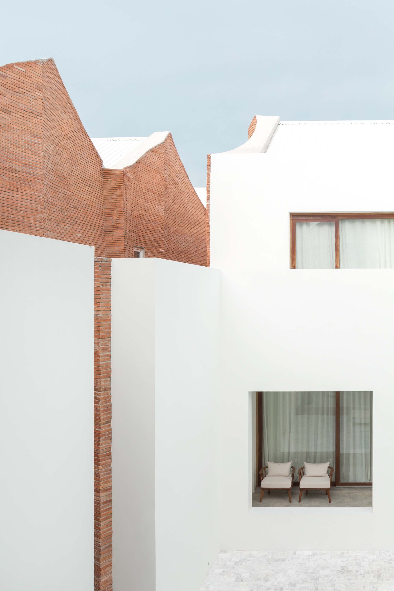 Sala Ayutthaya Resort exterior with serrated-edge brick walls and white facade featuring window with interior seating visible.