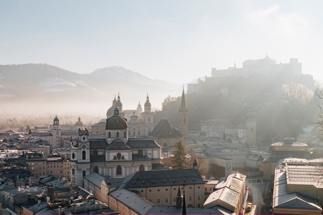Aerial view of Salzburg's historic city center with baroque churches, domed buildings, and fortress on hillside