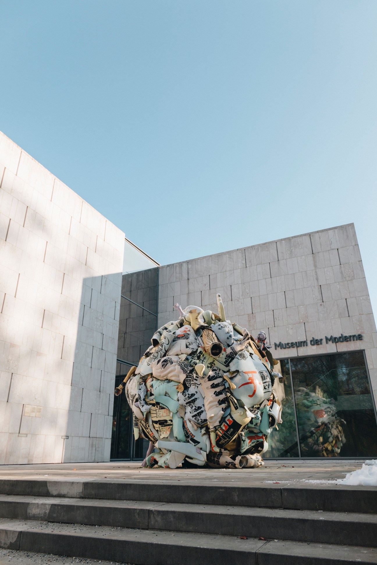 Large sculptural sphere made of crumpled materials outside Museum der Moderne Salzburg's modern concrete building