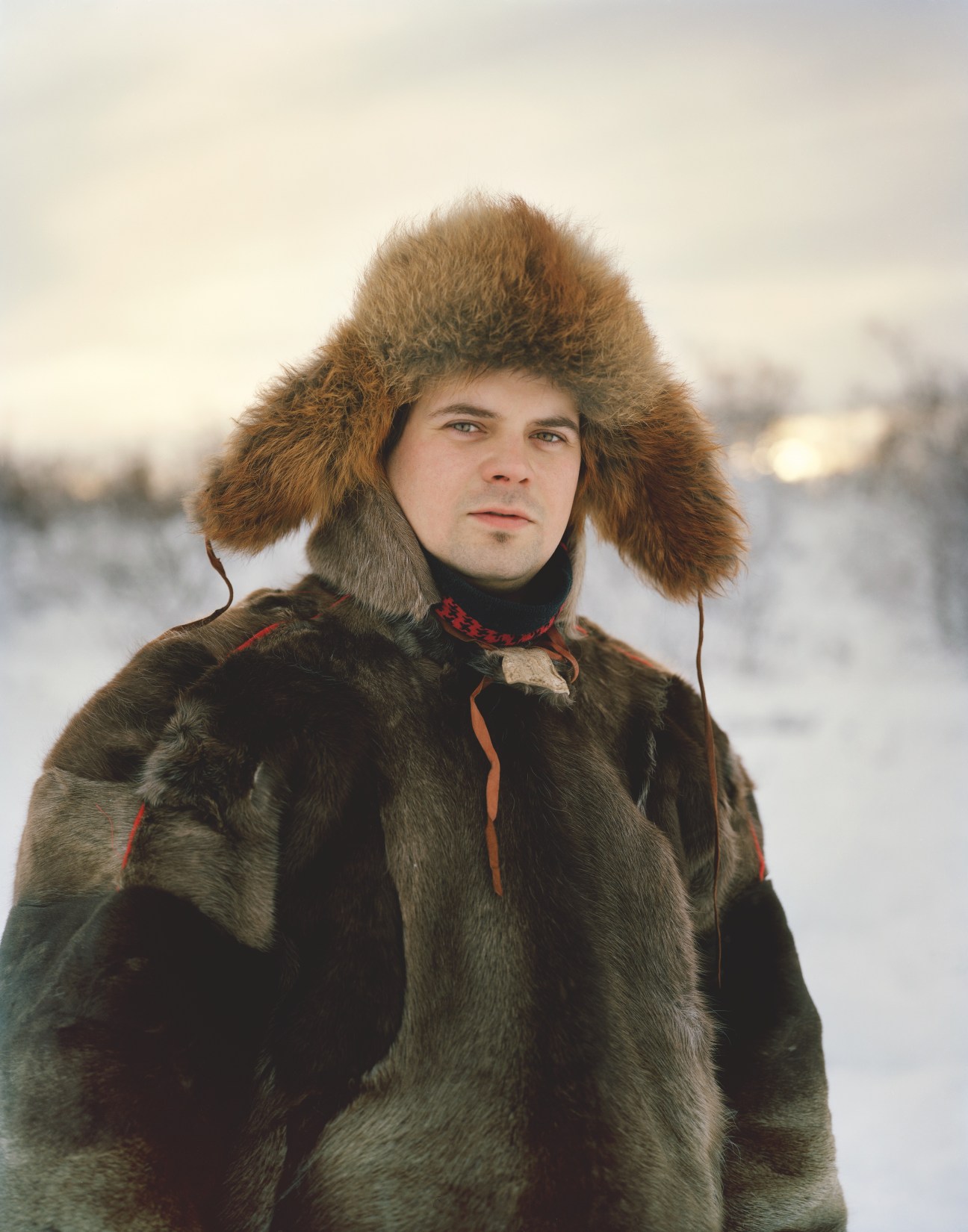 Per Anders Eira, a Sámi reindeer herder, wearing traditional fur clothing and hat in a snowy landscape.