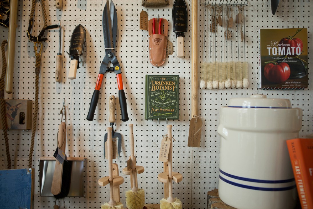 Garden tools and books displayed on pegboard wall at Modern General store.