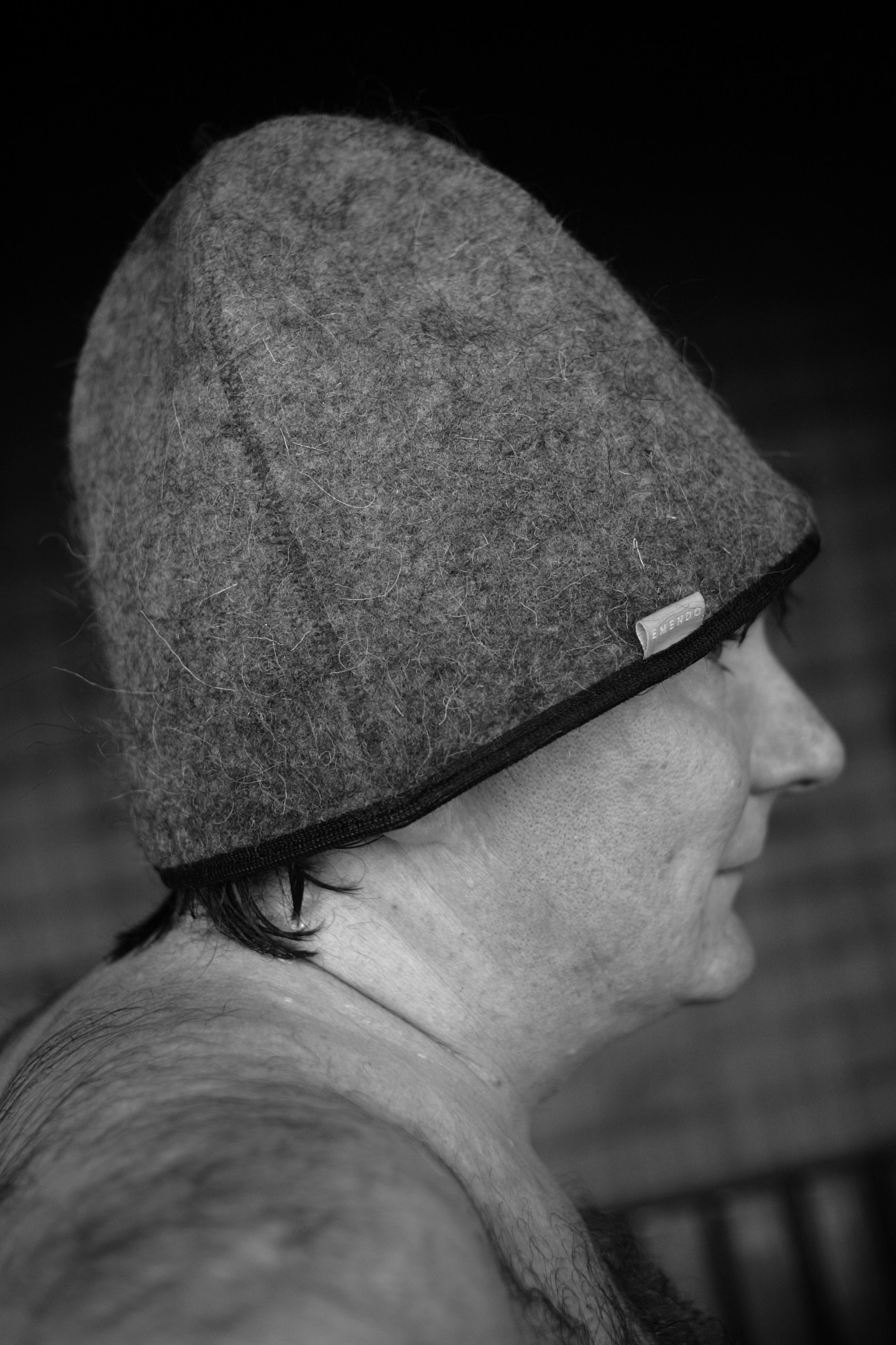 Person wearing a gray wool beanie hat with black band shown in profile against dark background.