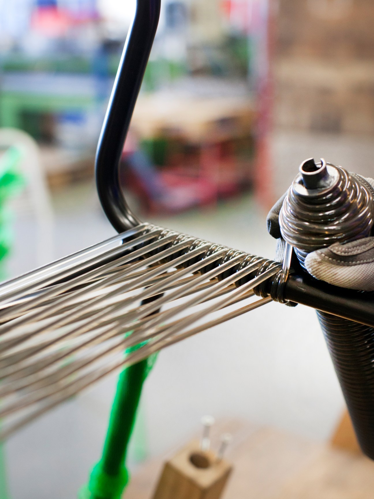 Close-up of metal frame and woven seat being braided during Spaghetti chair manufacturing.