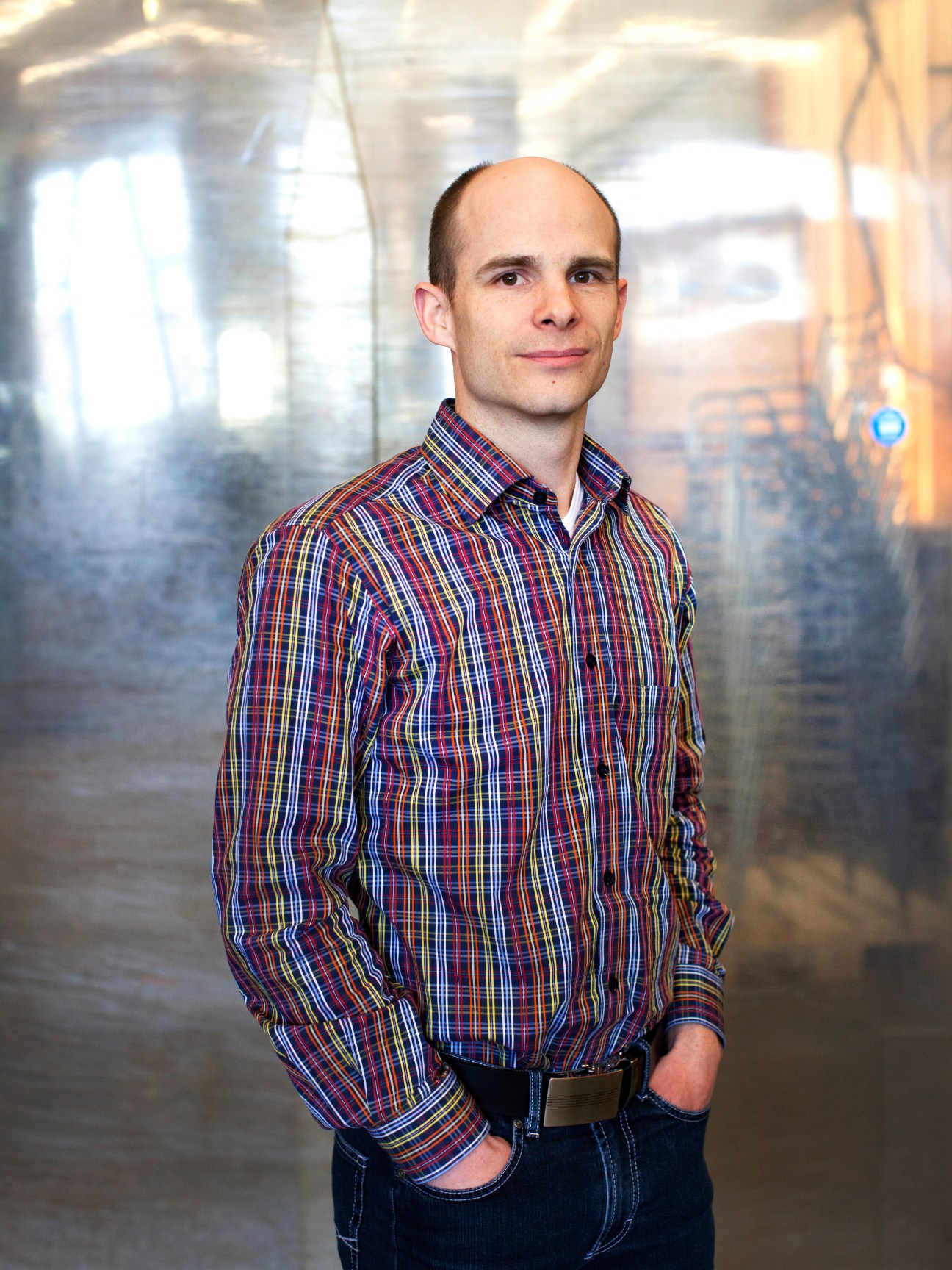 Samuel Schaffner stands in his workshop wearing a red and blue plaid shirt.