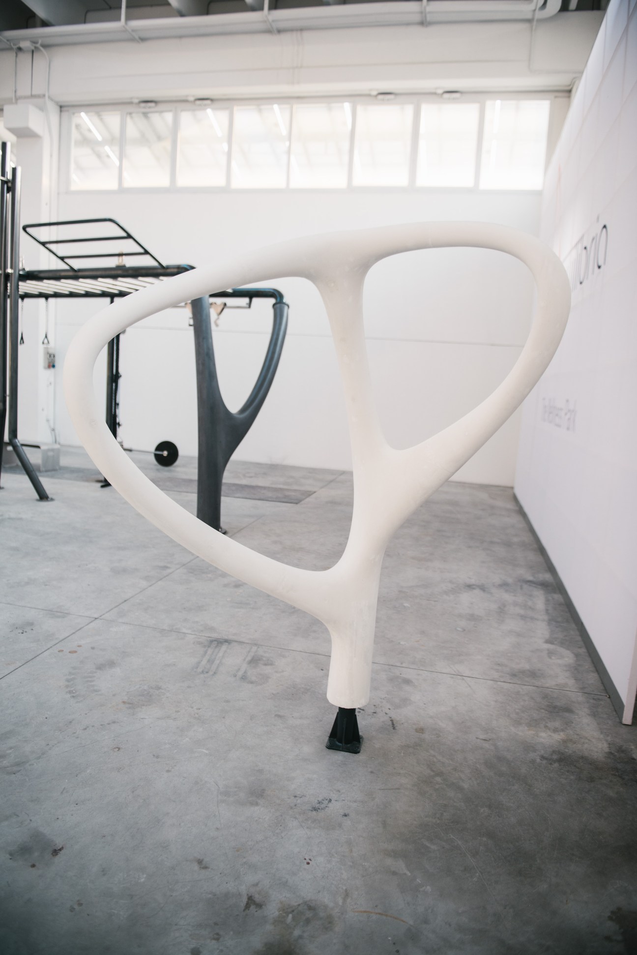White concrete leaf-shaped exercise equipment with integrated fitness machine in a bright showroom.