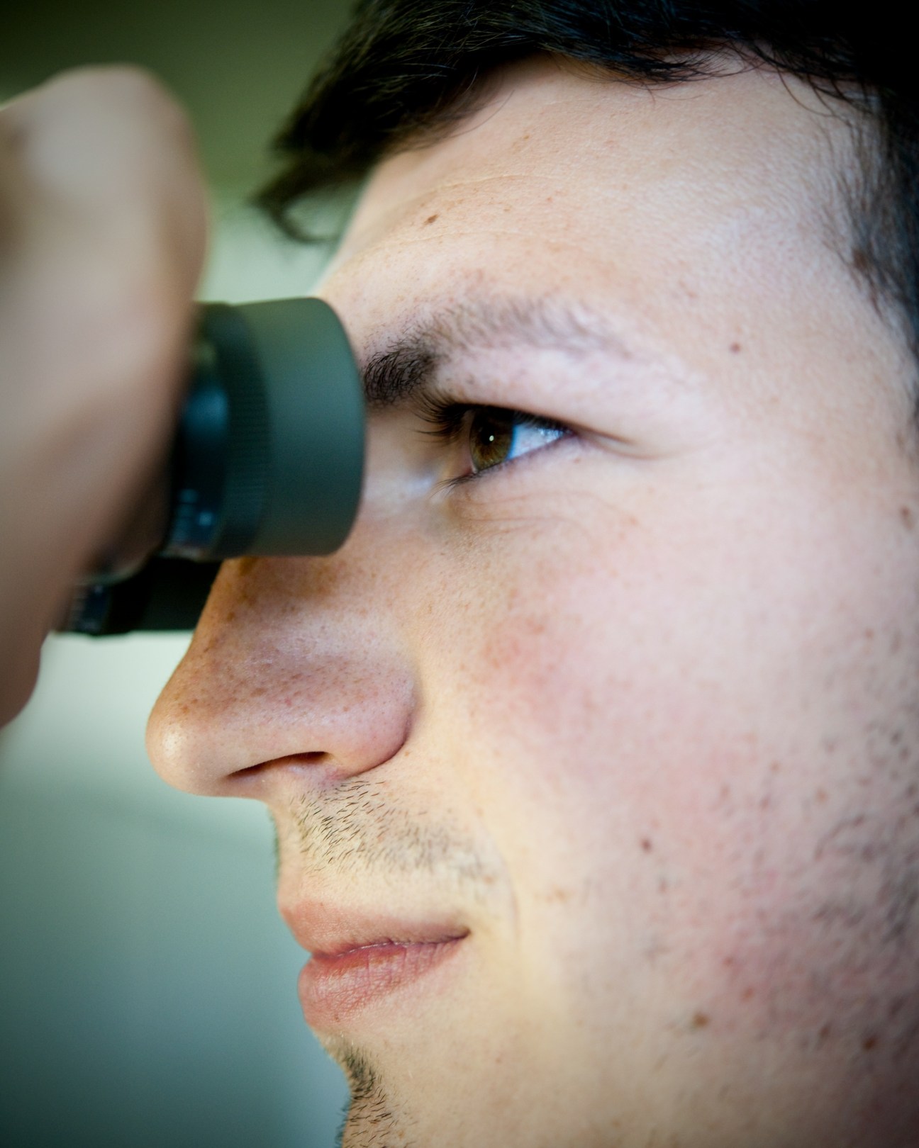 Man in profile holding Steiner binoculars up to his eye for quality control testing.