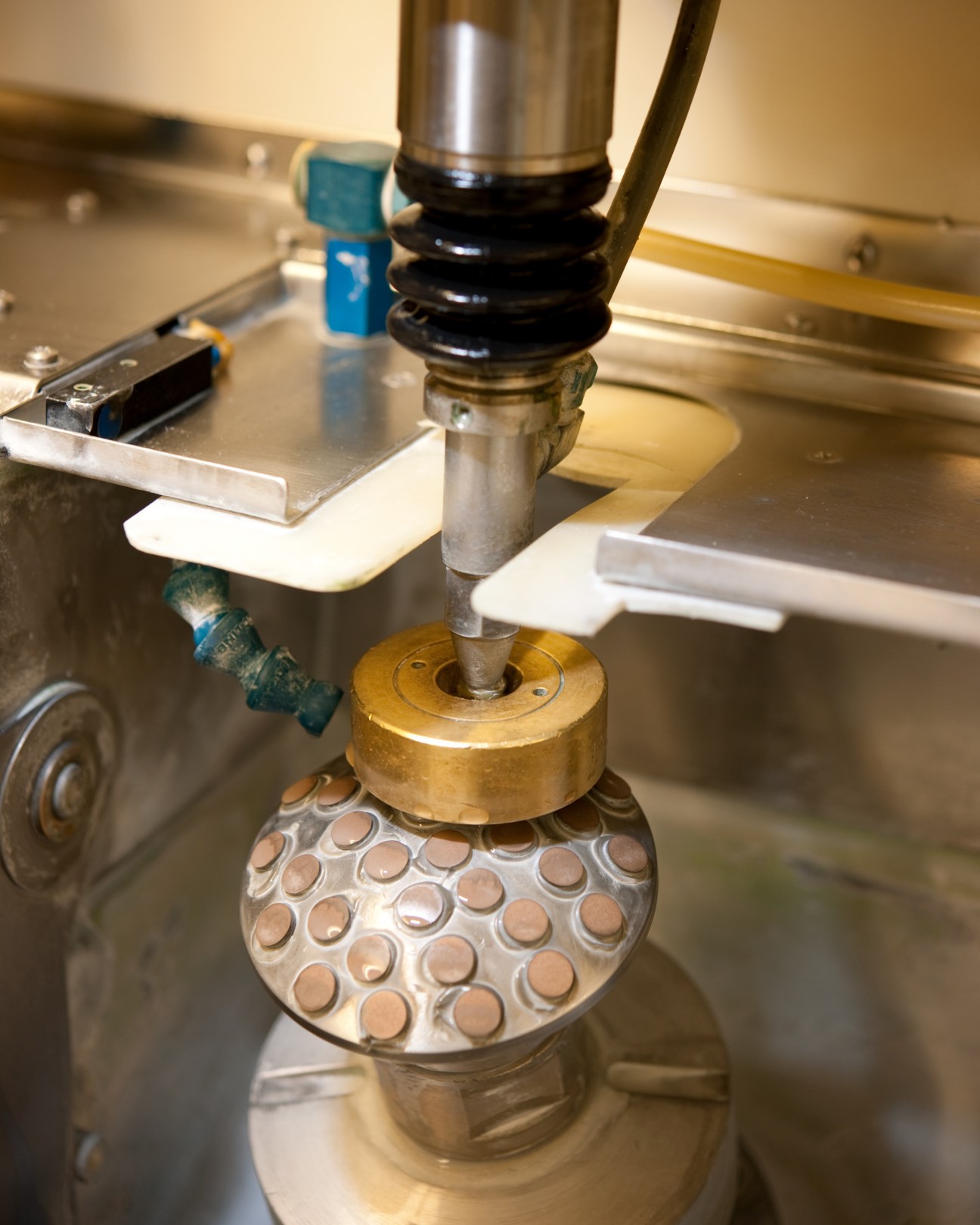 A CNC machine tool smoothing a glass lens disc with diamond dust at Steiner's manufacturing facility.