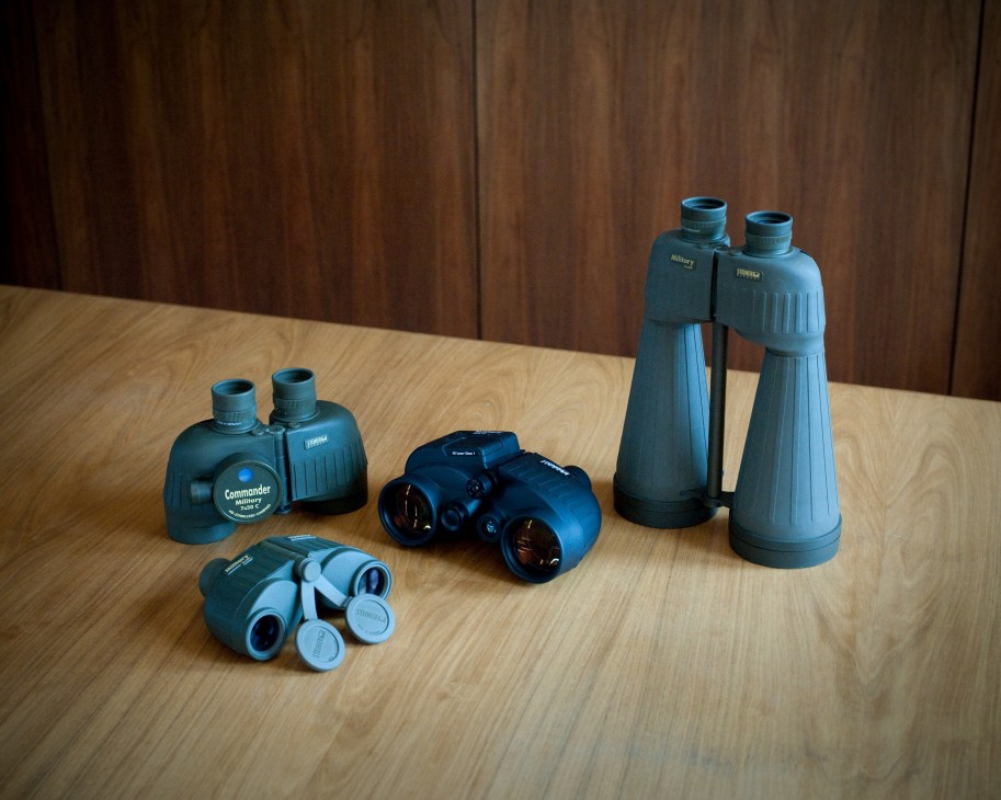 Steiner military and law-enforcement binoculars displayed on a wooden table.