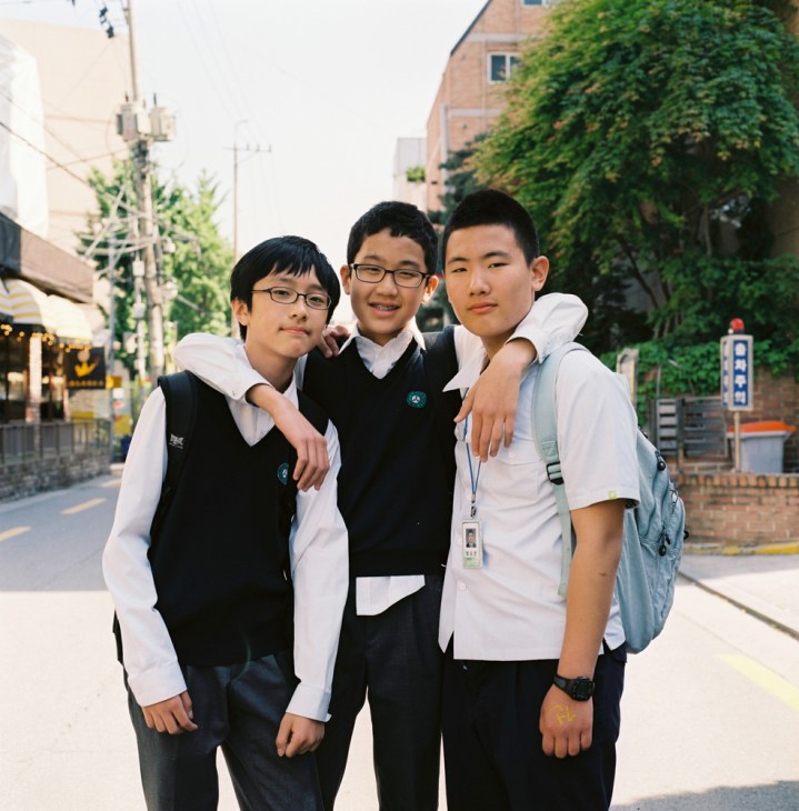 Three Korean schoolboys in uniforms posing together on a street in Seoul's Sinsa-dong neighbourhood.