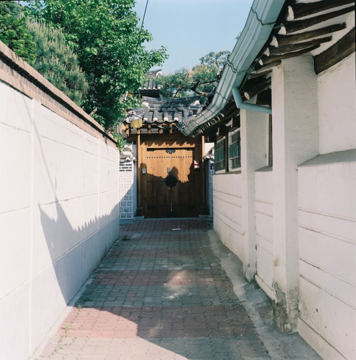 Traditional Korean hanok house with wooden gate and tiled roof in narrow Seoul alley