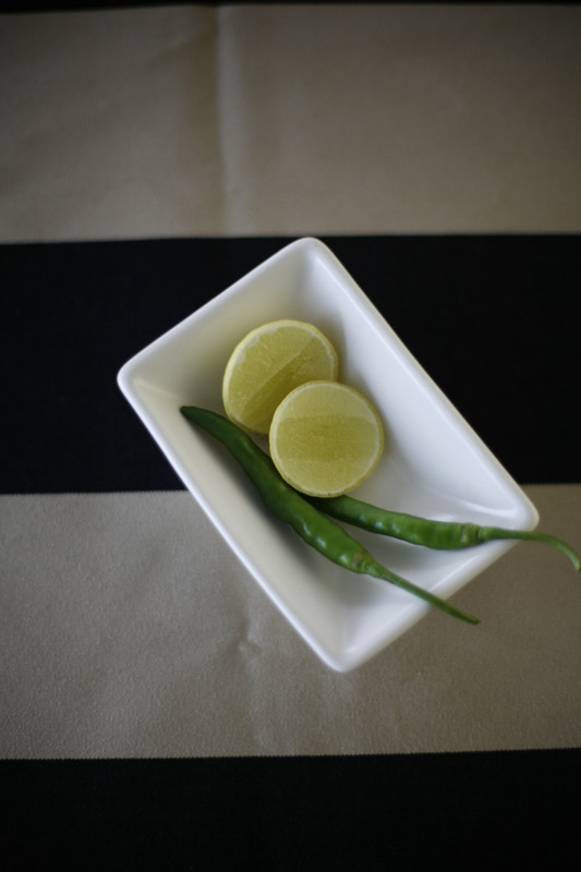 White rectangular dish with lemon slices and green chilli garnish.