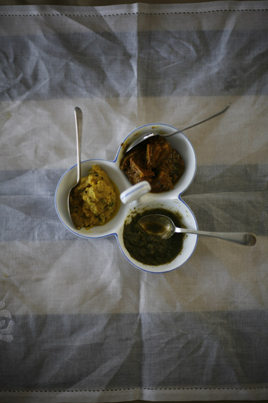 Three bowls of different flavoured chutneys with spoons on a light linen cloth.