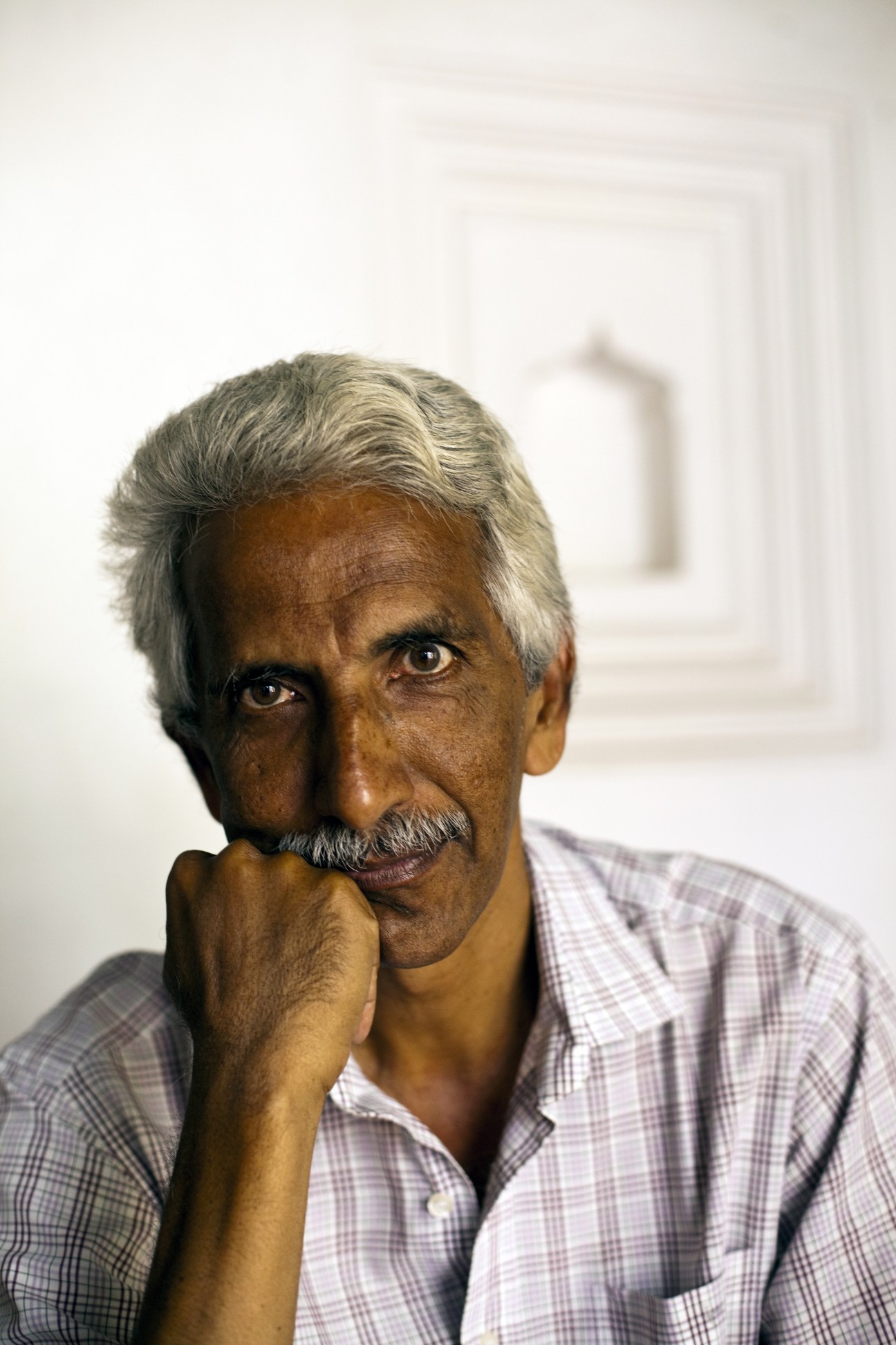 Ashok Panda, head of Pondicherry's Intach chapter, poses for a portrait with his hand near his face.