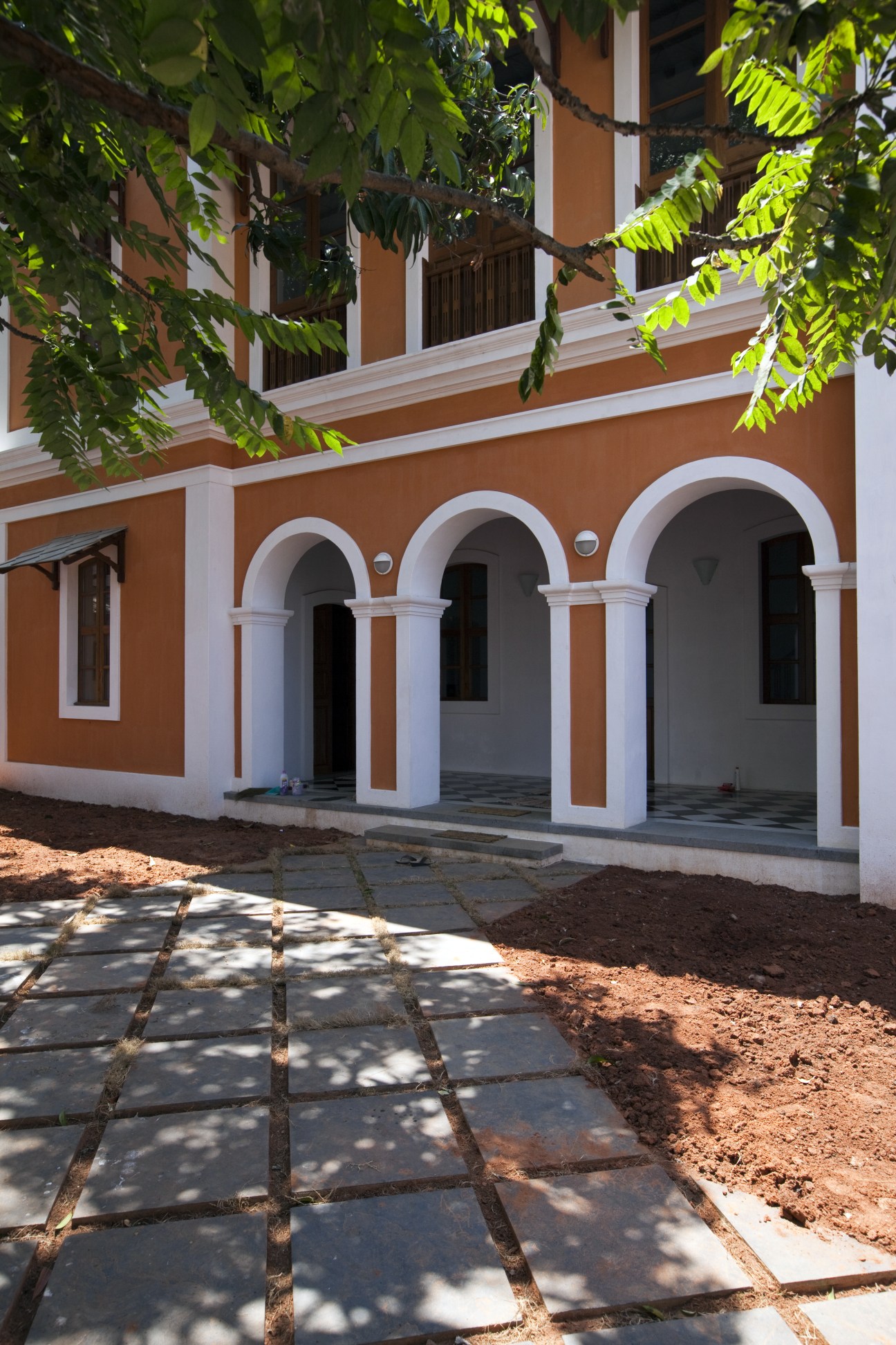 Colonial-style building with terracotta walls, white arches, and columns in Pondicherry.