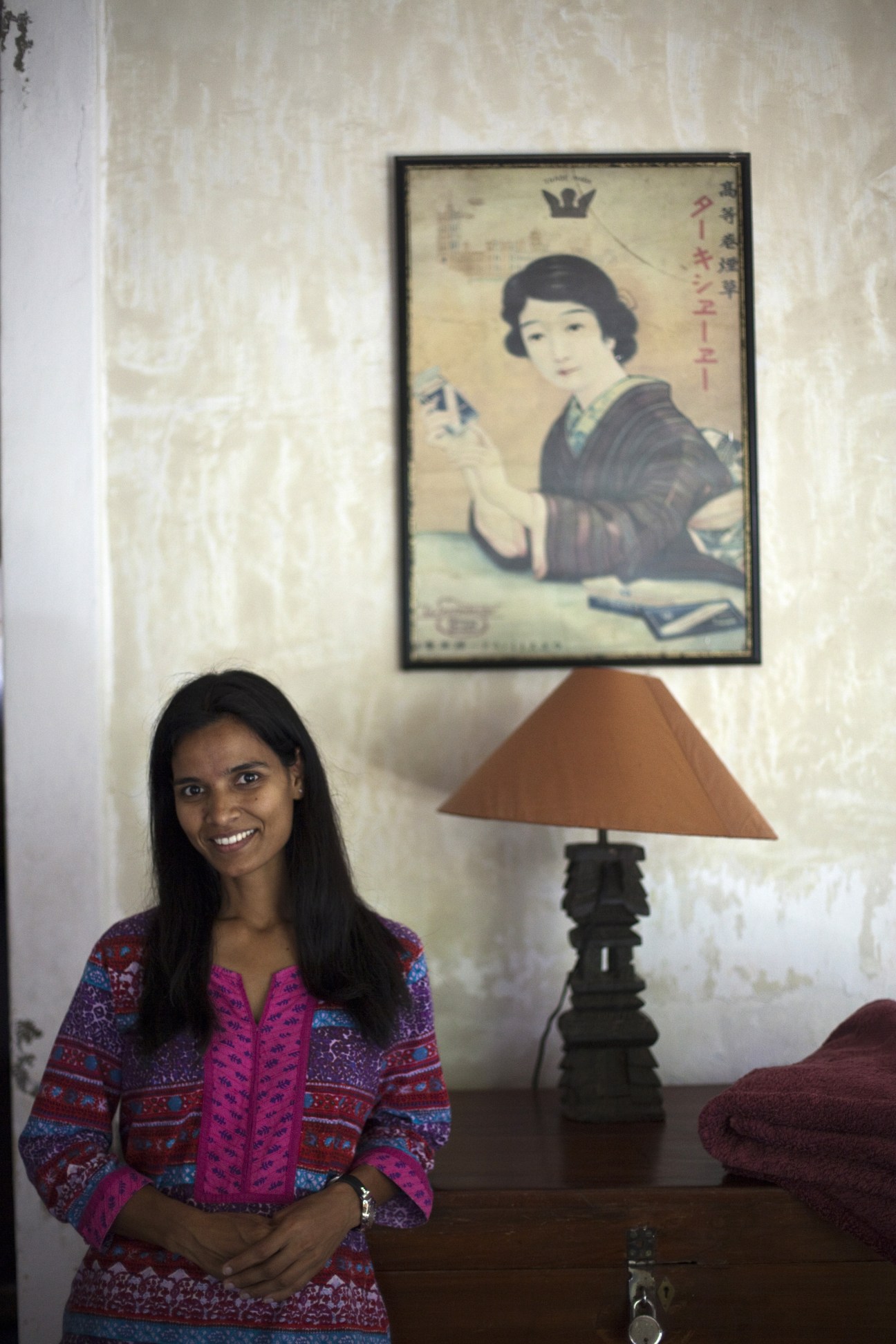 Woman in colorful patterned jacket smiling at camera inside Villa Helena guesthouse.