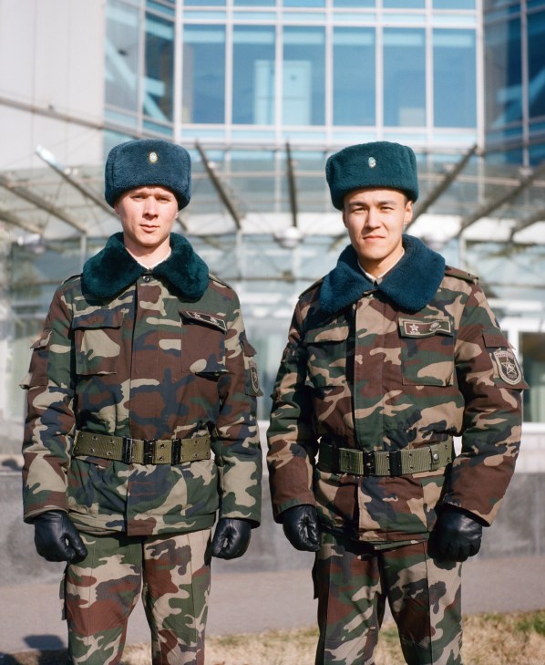 Two uniformed members of Kazakhstan's presidential guard stand in front of a modern building.