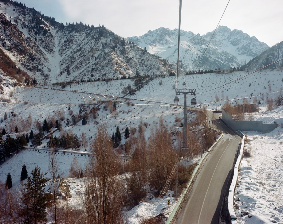 Soviet-built anti-mudflow dam in snowy Medeu Valley with mountains, cable car, and forested slopes.