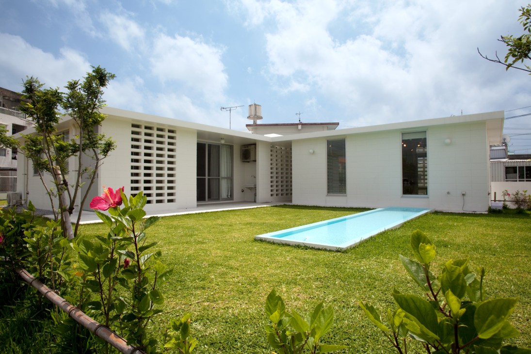 Modern white concrete Okinawa Standard house with terrace, hollow hana blocks, lush garden and small pool.