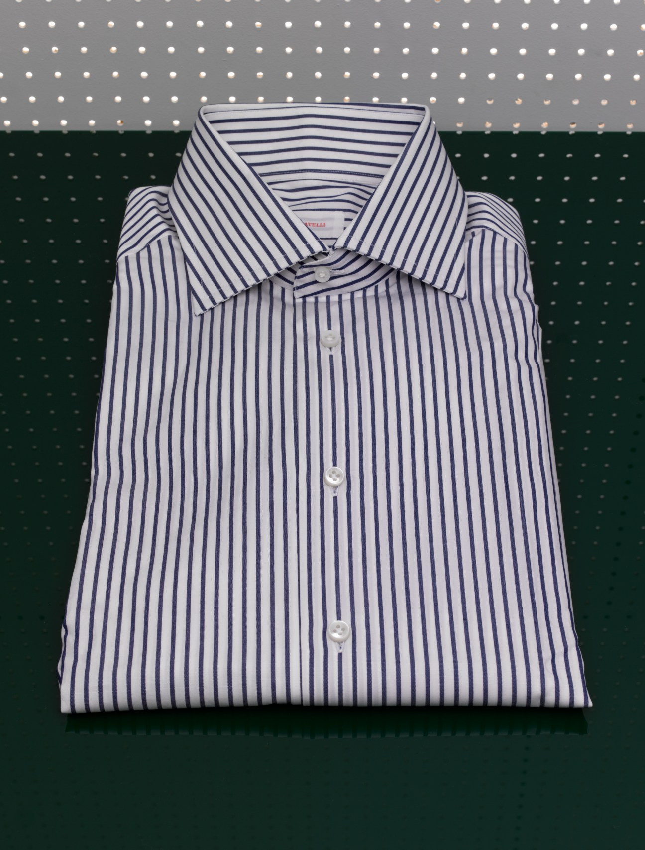 Folded white dress shirt with navy blue stripes and mother-of-pearl buttons from Fratelli.