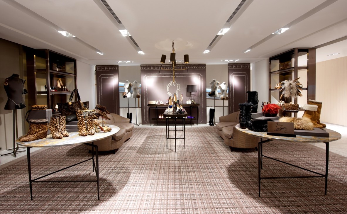Luxury shoe gallery interior with leopard-print boots displayed on rounded tables and wall-mounted displays.