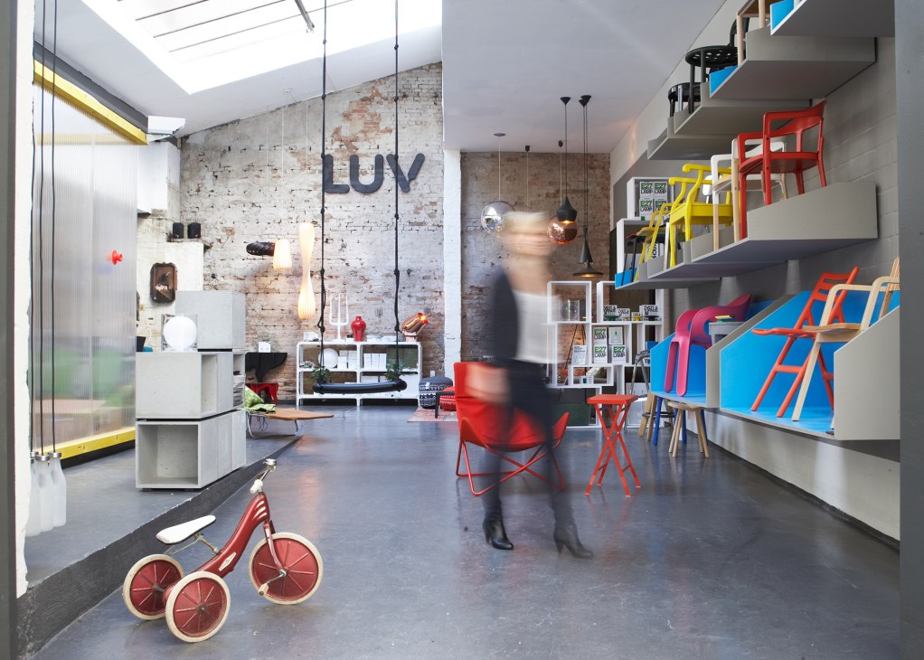 Interior of Luv concept store in Hamburg with Scandinavian design furniture, exposed brick walls, and colorful chairs on display.
