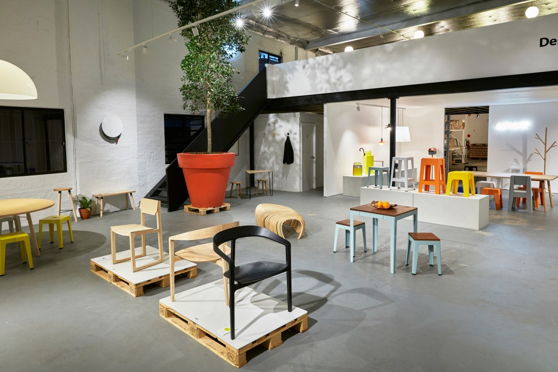 DesignByThem showroom interior in Sydney displaying various chairs, tables, and stools in wood and colourful finishes.
