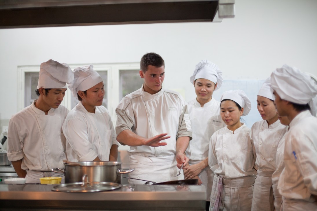 A chef instructs trainee cooks in a professional kitchen at Shwe Sa Bwe restaurant in Yangon.